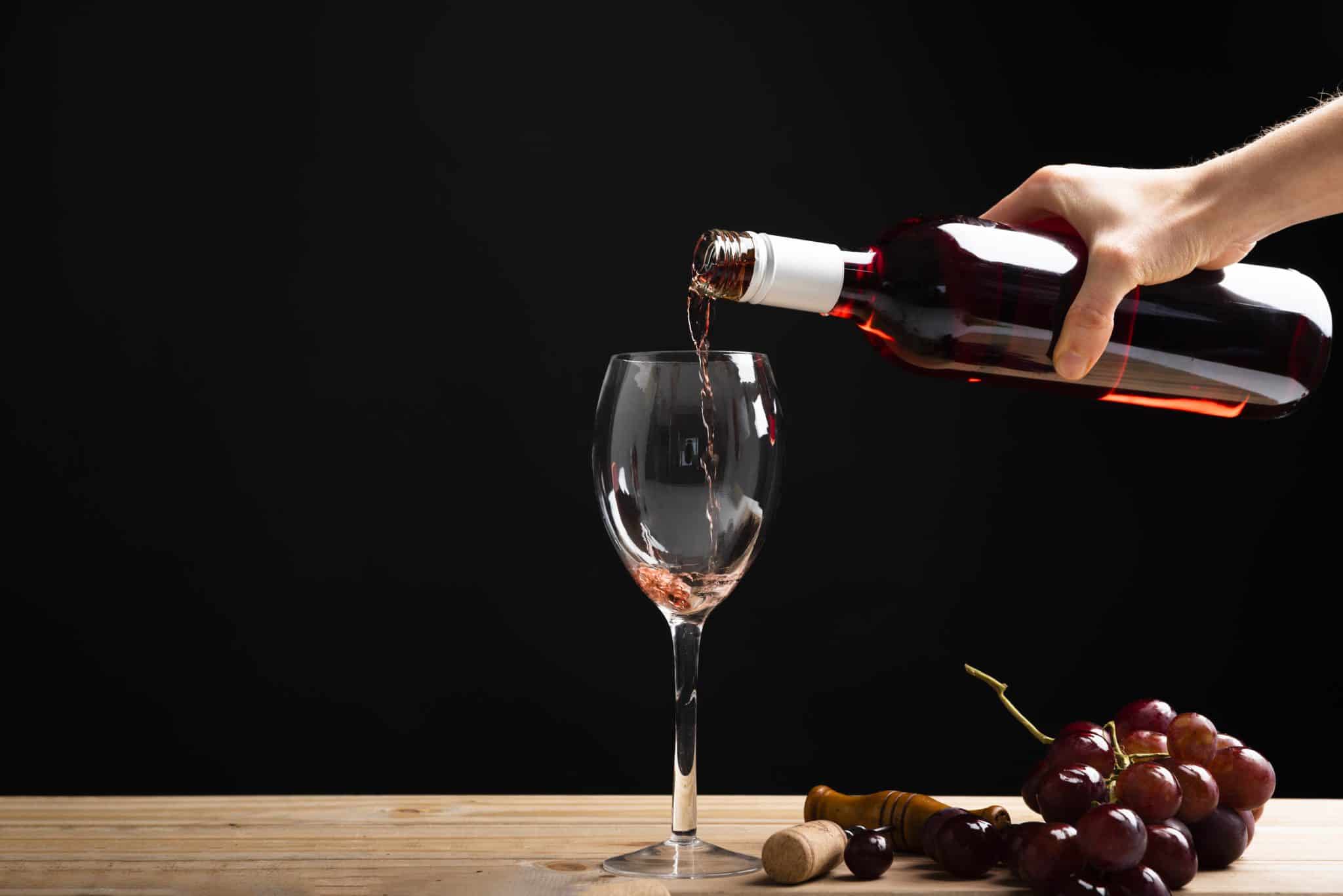 בקבוק יין נשפך לתוך כוס עם רגל