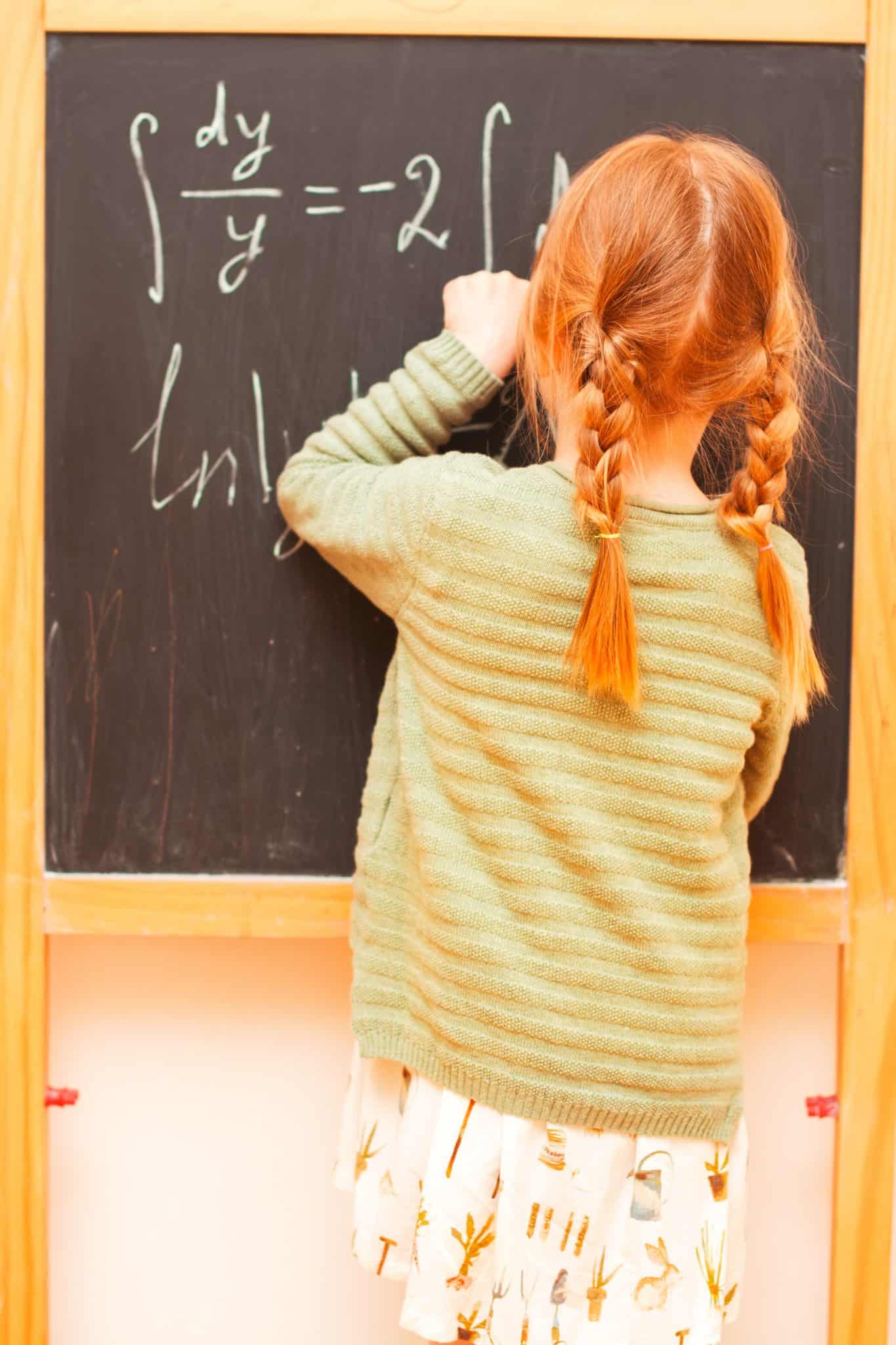 ילדה עם שתי צמות כותבת על לוח גיר